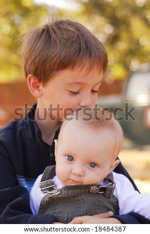 Big brother kissing his little brother on the head at a farm