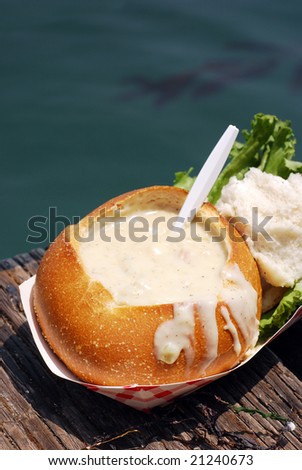 Clam chowder in a sourdough bread bowl on a wooden fishing dock