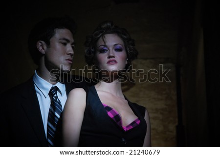 Seedy couple standing in the shadows of a dark hallway