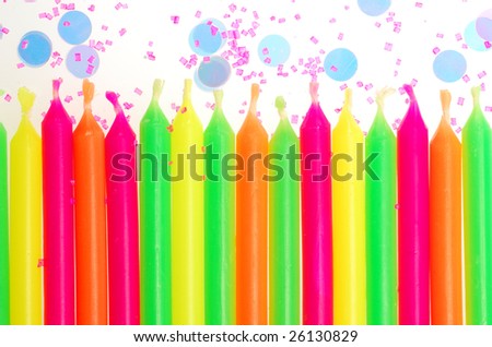Row of unlit birthday candles with confetti and cake sprinkles