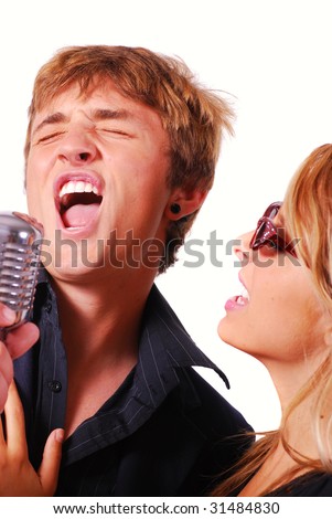 stock photo Teen couple singing into retro microphone at karaoke