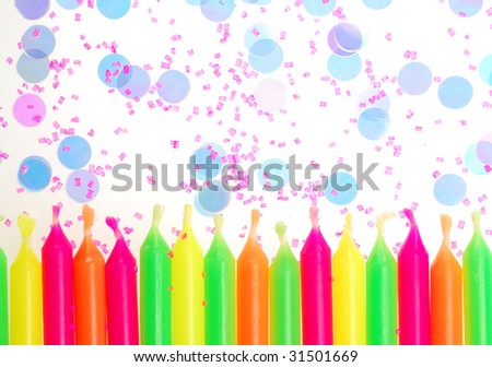 Row of unlit birthday candles with confetti and cake sprinkles