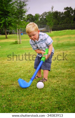 Caucasian toddler playing at park with toy golf club