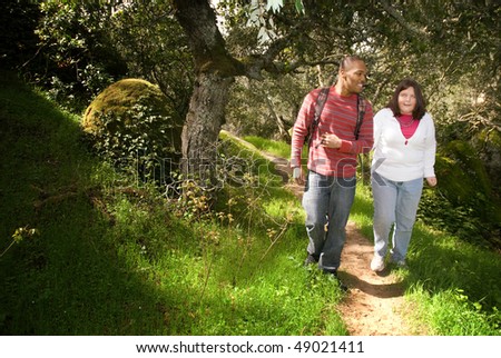 Young man walking with his visually impaired friend on a forest path using sighted guide technique