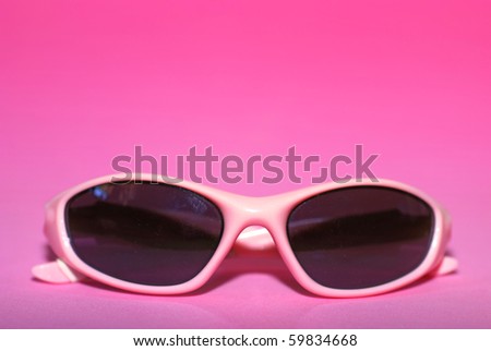 Pair of pink women\'s sports sunglasses on a pink background