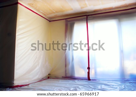 Room covered with clear plastic sheeting after asbestos abatement completed on popcorn ceiling