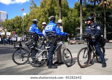 SACRAMENTO, CALIFORNIA - FEBRUARY 26: Law Enforcement officers watch Tea Party protesters (in back, left) in Sacramento, California on February 26, 2011