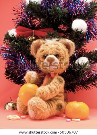 Toy knitting tiger with oranges under a christmas fur-tree