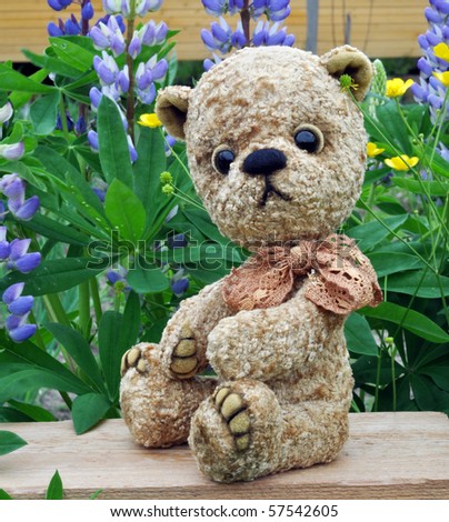 Handmade, the sewed toy: teddy-bear Misha among flowers lupine and buttercups
