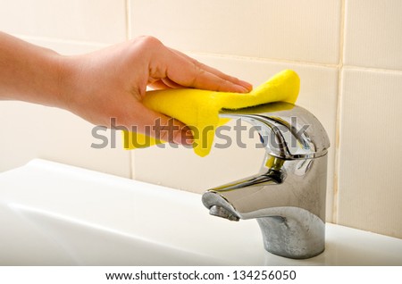 hand cleans tap with sponge