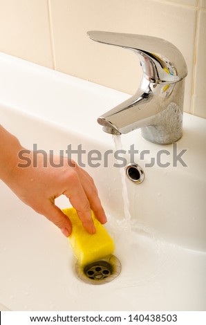 hand cleans tap with sponge
