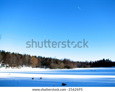 Winter scene of a frozen lake (the moon and a plane in the background)
