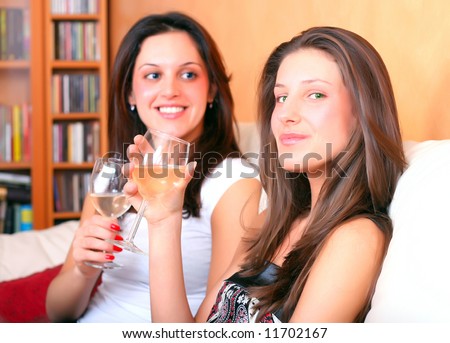 Two young ladies sitting on a couch and having a glass of wine
