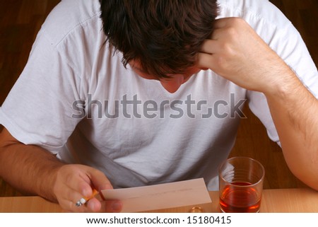 Sad man looking into the photo of a lost love (or a child) while consuming alcohol (conceptual)