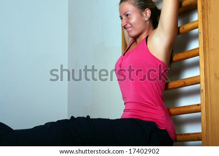 Young lady at the gym in sports position stretching