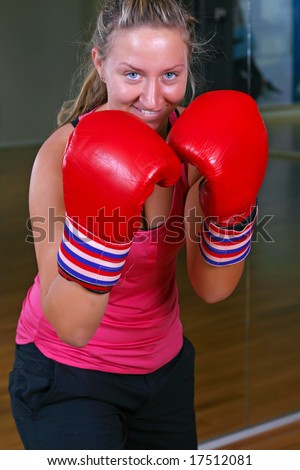 Sporty girl in boxing gloves punching (action shot)