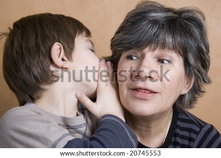 Little boy whispering to his grandmother