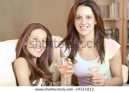 Retro photo of two young ladies sitting on a couch and having a glass of wine