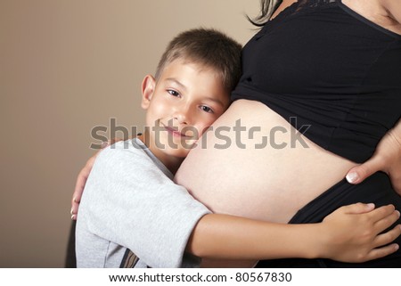 A happy boy hugging expecting mom\'s belly