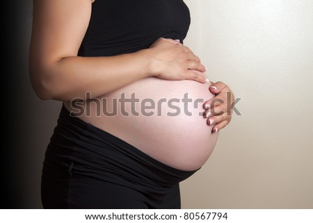 Beautiful pregnant belly of a future mother with hands around wearing black