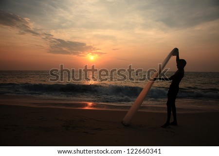 Silhouette of a fisherman works with his net during sunset