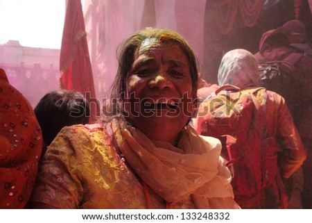 BARSANA - MAR 21: An old woman celebrates Holi by throwing colors at Radharani temple on March 21, 2013 in Barsana, India. Holi is the most celebrated festival in India.