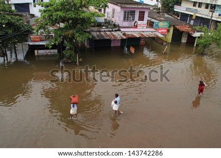 KUTTANAD, INDIA - JUNE 26:Unidentified people walk on the flood water on June 26,2013 in Kuttanad, India. Kuttanad is an area below sea level and is often affected by flood during heavy rains