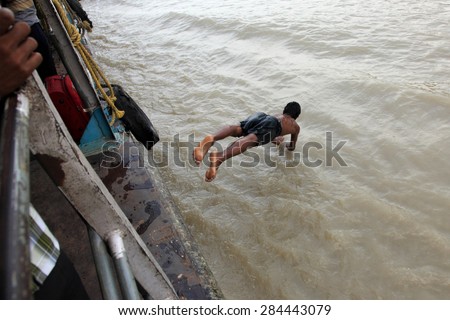KOLKATA,INDIA- OCT 16: An unidentified young man performs stunt on a moving boat in Hoogly river on October 16, 2010 in Kolkata, India.It is a usual practice to impress visitors and earn extra money.