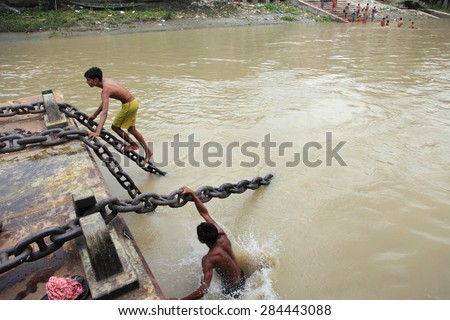 KOLKATA,INDIA- OCT 16: An unidentified young men performs stunt on a moving boat in Hoogly river on October 16, 2010 in Kolkata, India.It is a usual practice to impress visitors and earn extra money.