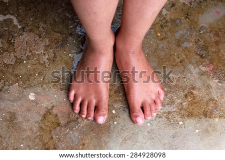 Wet feet of a child on a rough cement floor