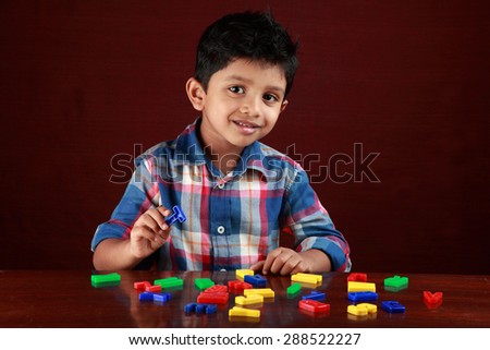 A small kid looks as he plays with toy alphabets in dark background