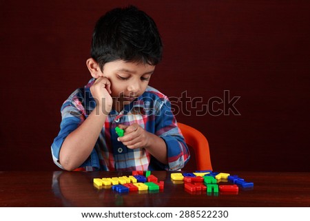 A small boy plays with toy alphabets in a dark background