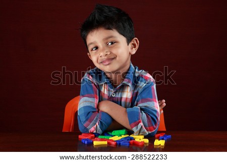 A small kid looks as he plays with toy alphabets in dark background