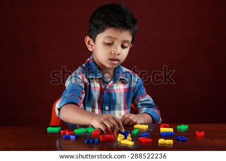 A small boy plays with toy alphabets in dark background