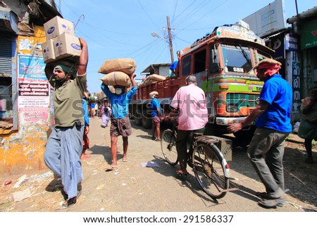 KOCHI, INDIA -FEB 02: Unidentified head load workers unloading gunny bags from a truck in the market on February 02, 2012 in Kochi, India. Head load workers are an organised work force in Kerala.