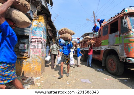KOCHI, INDIA -FEB 02: Unidentified head load workers unloading gunny bags from a truck in the market on February 02, 2012 in Kochi, India. Head load workers are an organised work force in Kerala.