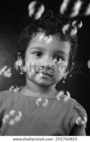 Black and white image of little girl playing with bubbles