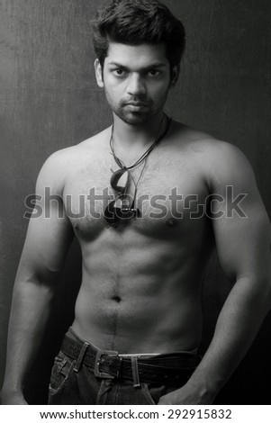 Light and shade monochrome portrait of a young man without a shirt against dark background