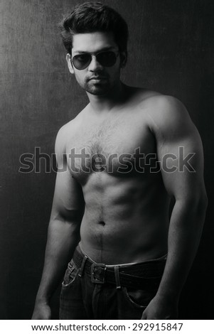 Light and shade monochrome portrait of a young man without a shirt against dark background