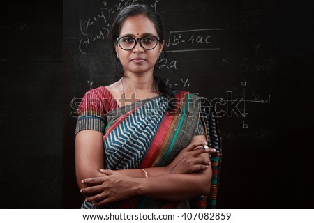 Portrait of Indian lady teacher stands in front of a blackboard