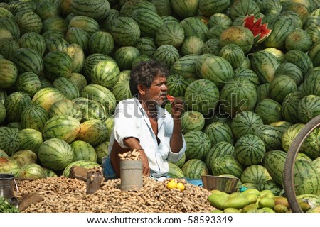 CHENNAI - MAR 15 : A street seller of fruits eats a piece of watermelon during the scorching summer heat March 15, 2009 in Chennai, India.  At summer Chennai temperature ofter crosses 40 degree C.