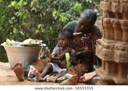 CHENNAI - MAR 15 : A street seller with a small boy selling cucumber to public  March 15, 2009 in Chennai, India. Children of economically backward are  brought to business at a younger age