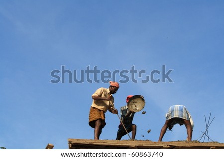 ALLEPPEY, INDIA - OCT 31 : Construction workers working on a building roof October 31, 2009 in Allepey, India. In India building workers are not bothered to wear any safety measures at work.