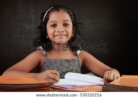 A little girl smiles as does her homework in the study room