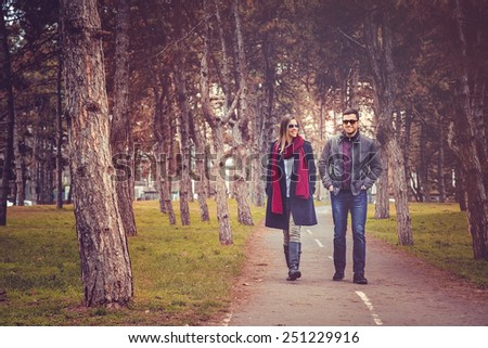 Happy couple walking in autumn city park
