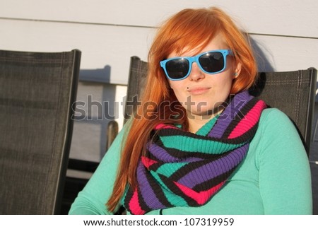 Young redhead woman relaxing on a patio in spring.