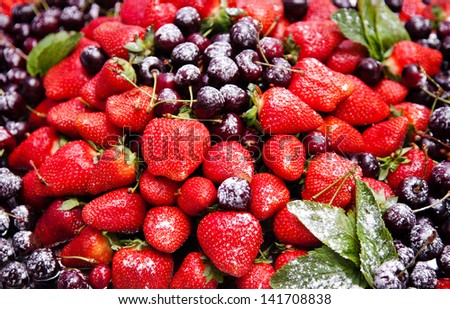 Ripe and juicy berries and cherries strawberries, sprinkled with powdered sugar