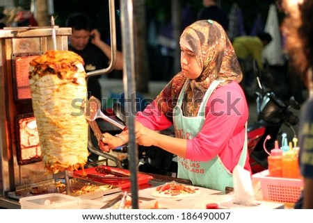 PATTAYA, THAILAND - MARCH 14: Thai woman cook and sells grilled chicken and fish on March 14, 2014 in Pattay, Thailand