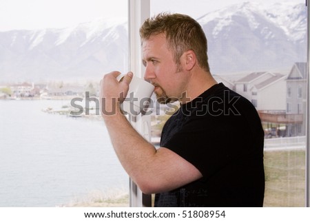 Man by the Bedroom Window with a Cup of Coffee in the Morning