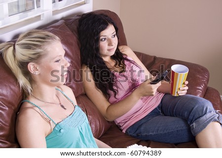Two Girls Sitting on the Sofa Watching a Movie and Eating Pop Corn